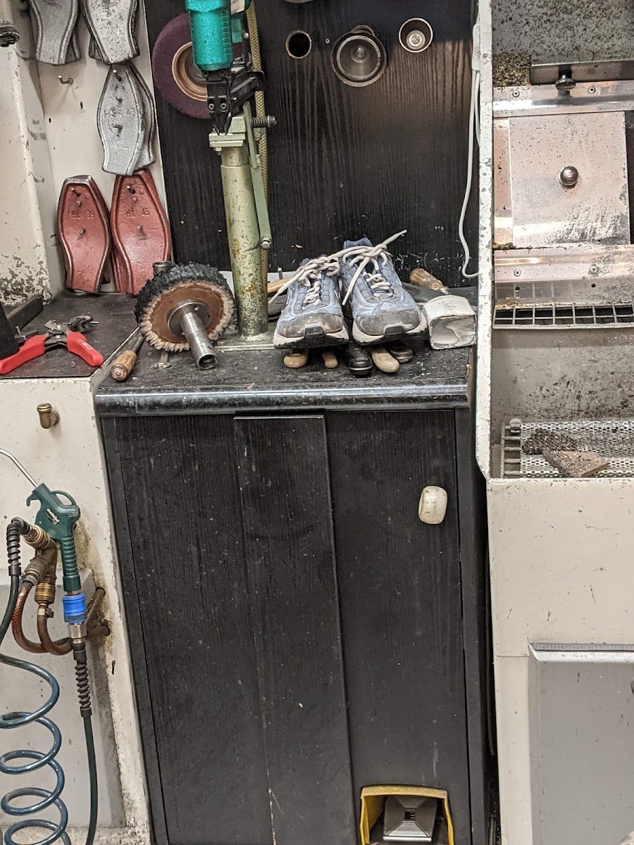 Werkbank mit Poliermaschine und Schuhen in Reparatur